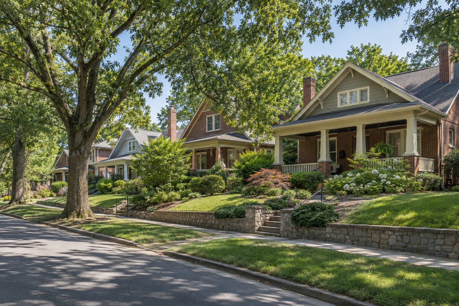 Older brick and craftsman homes beneath mature oak trees on a quiet Greensboro street