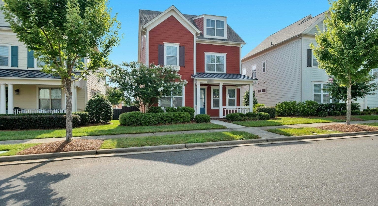 A red home with a front porch on a tree-lined street in Pineville, near Charlotte